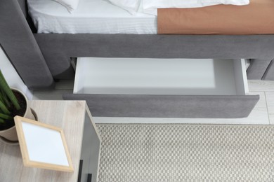 Storage drawer for bedding under modern bed in room, above view