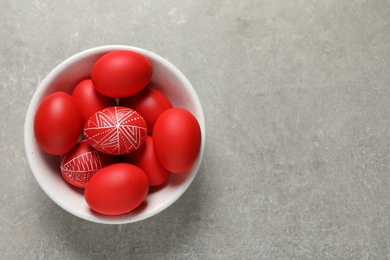 Photo of Bowl with red painted Easter eggs on table, top view. Space for text