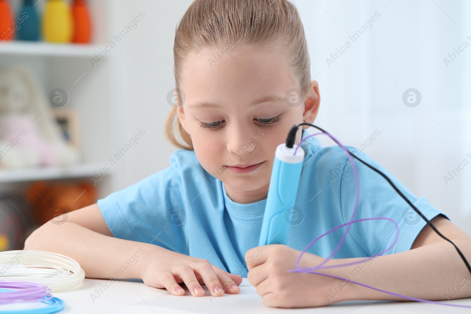 Photo of Girl drawing with stylish 3D pen at white table indoors