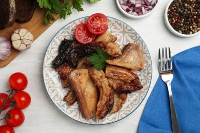 Tasty fried pork lard with parsley and tomatoes on white wooden table, flat lay