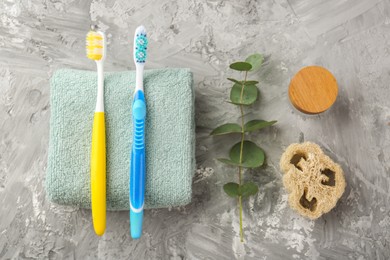 Photo of Flat lay composition with colorful plastic toothbrushes on grey textured table