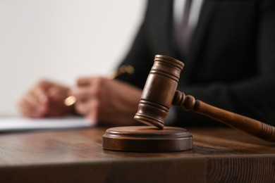 Photo of Law and justice. Closeup of judge working at wooden table, focus on gavel