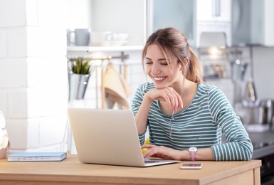 Image of Happy young woman working on laptop at home