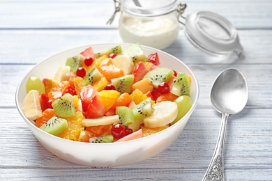 Photo of Bowl with fresh cut fruits on wooden table