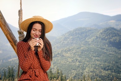 Photo of Young woman with hot drink resting in mountains on sunny day