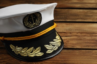 Photo of Peaked cap with accessories on wooden background, closeup. Space for text
