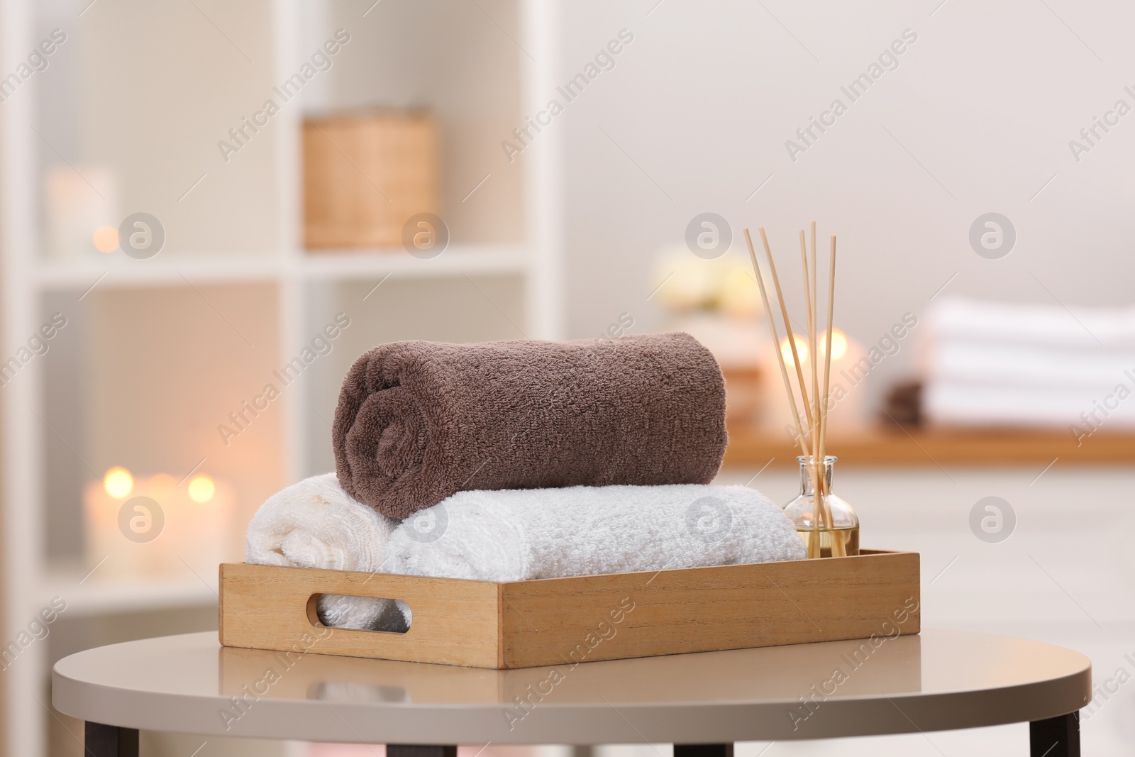 Photo of Tray with towels and reed air freshener on table in spa salon