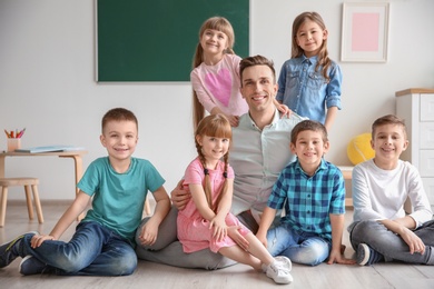Photo of Cute little children with teacher in classroom at school