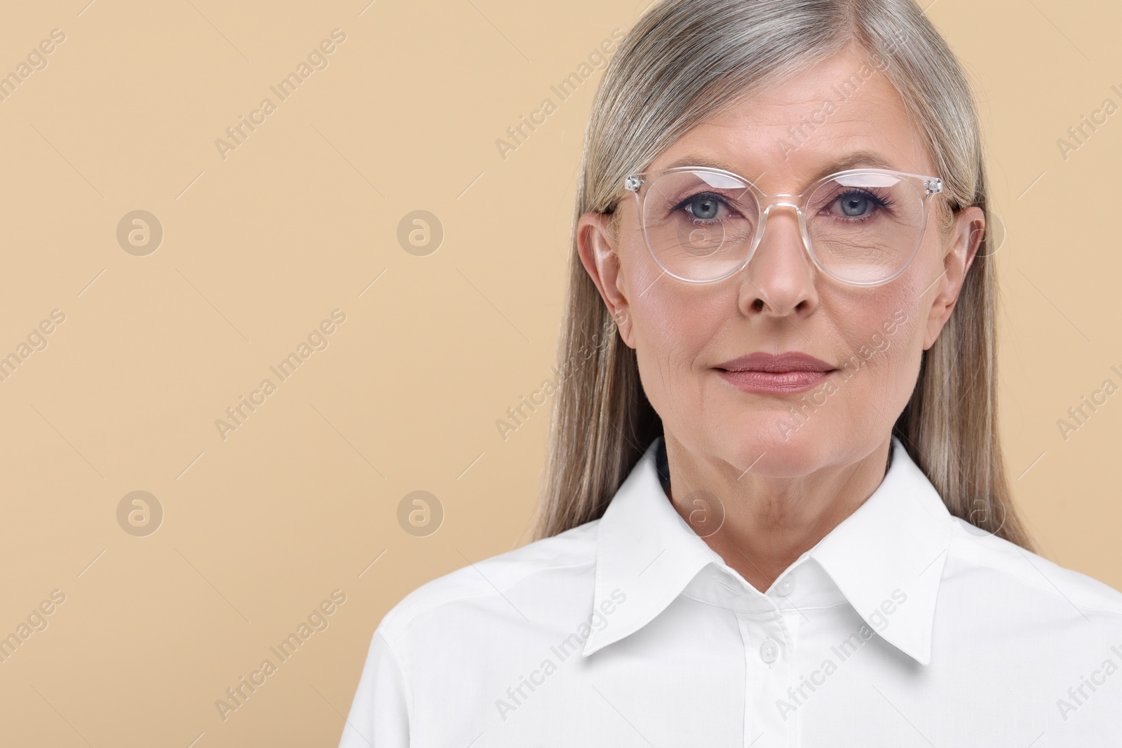 Photo of Portrait of beautiful senior woman in glasses on beige background. Space for text