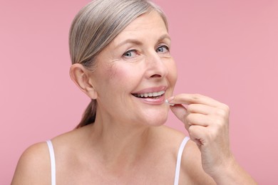 Photo of Beautiful woman taking vitamin capsule on pink background