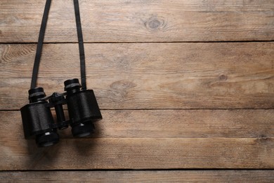 Photo of Modern binoculars on wooden table, top view. Space for text