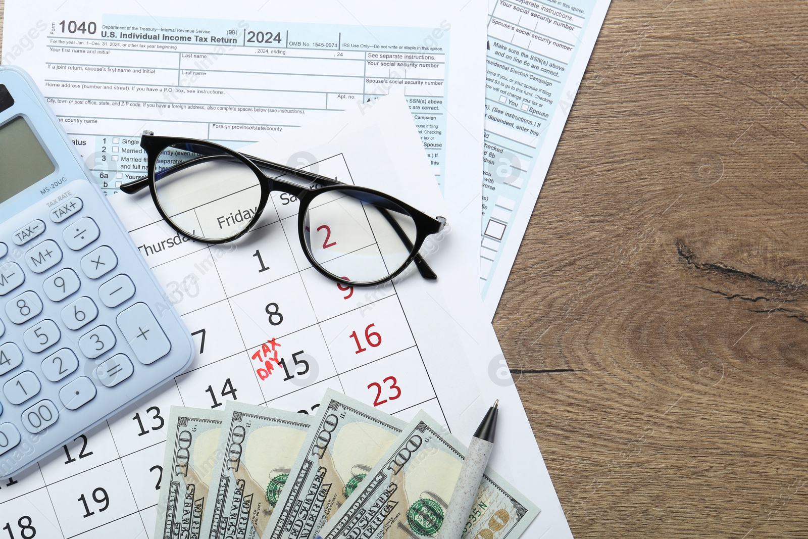 Photo of Calendar with date reminder about tax day, documents, money, calculator and glasses on wooden table, top view. Space for text