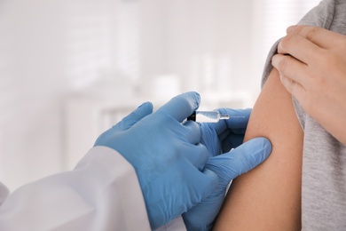 Photo of Doctor vaccinating woman against Covid-19 in clinic, closeup