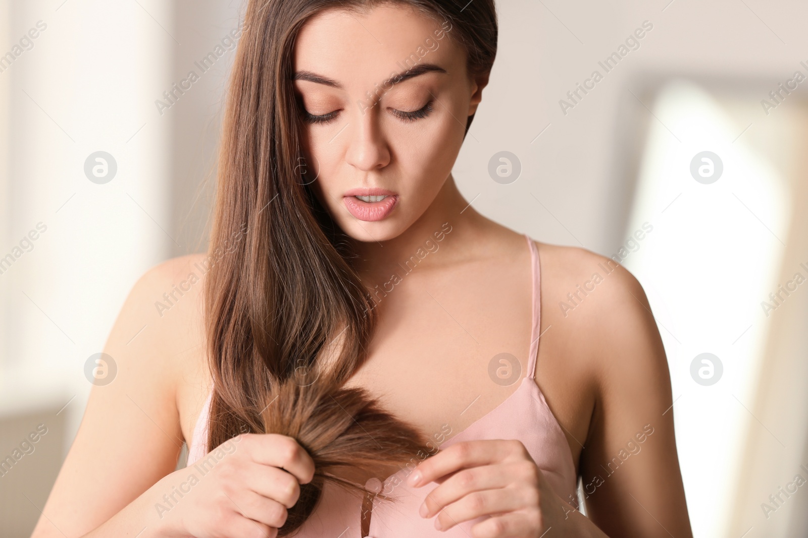 Photo of Emotional woman with damaged hair on blurred background. Split ends