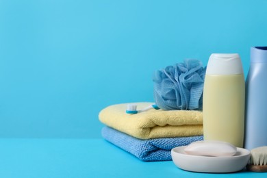 Photo of Baby cosmetic products, accessories and towels on light blue background. Space for text