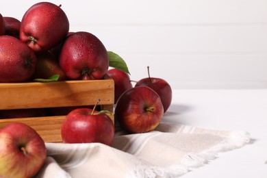 Photo of Fresh red apples in wooden crate on white table. Space for text