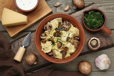 Delicious ravioli with mushrooms and ingredients on wooden table, flat lay