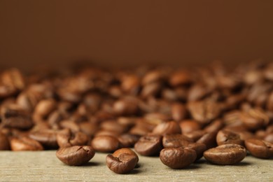 Photo of Many roasted coffee beans on wooden table, closeup