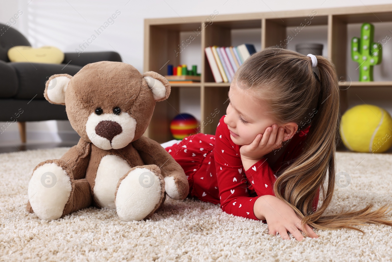 Photo of Cute little girl playing with teddy bear at home