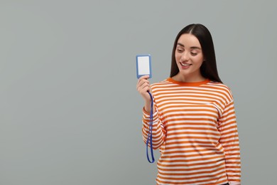 Happy woman holding vip pass badge on grey background, space for text