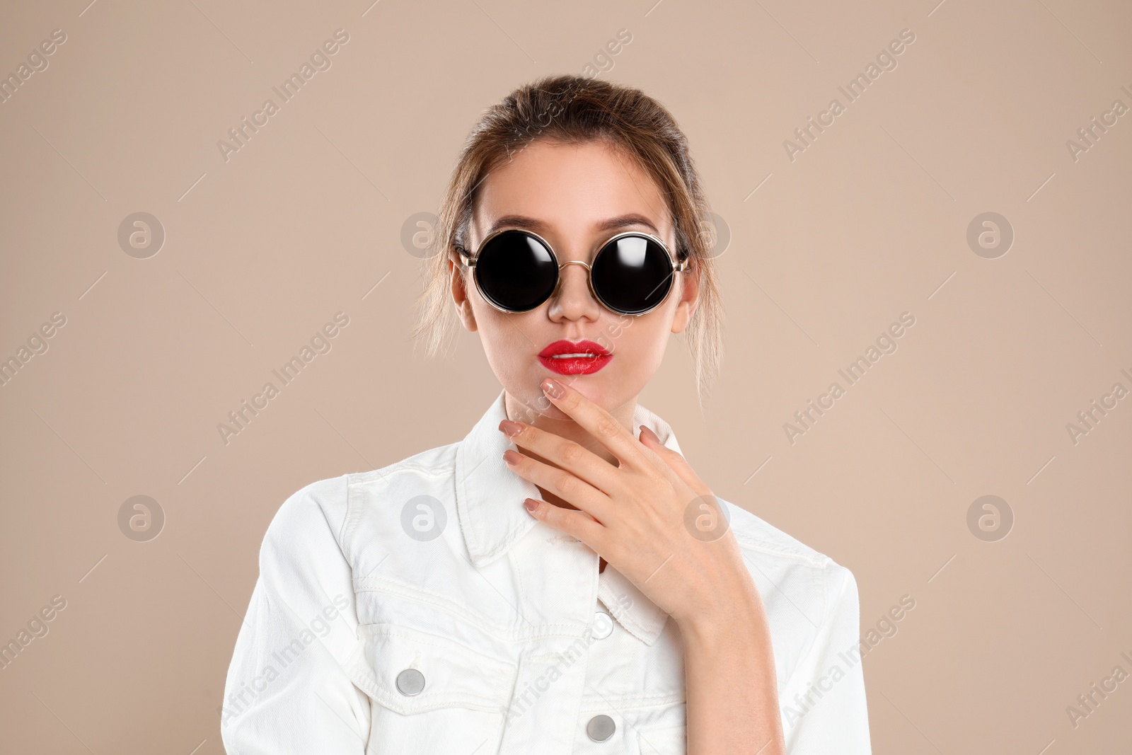 Photo of Young woman wearing stylish sunglasses on beige background