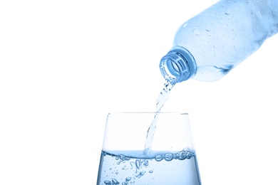 Pouring water from bottle into glass against blue background. Refreshing drink