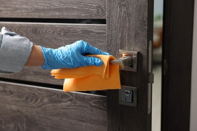 Photo of Woman wiping door handle with rag, closeup