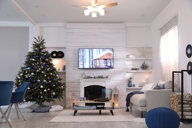 Stylish living room interior with modern TV, fireplace and Christmas tree