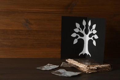 Photo of Card with family tree template, photos and album on wooden table. Space for text
