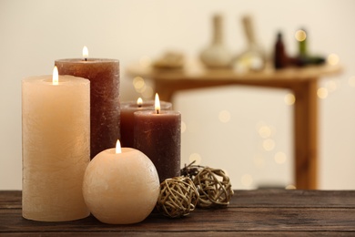 Burning candles on wooden table indoors. Space for text