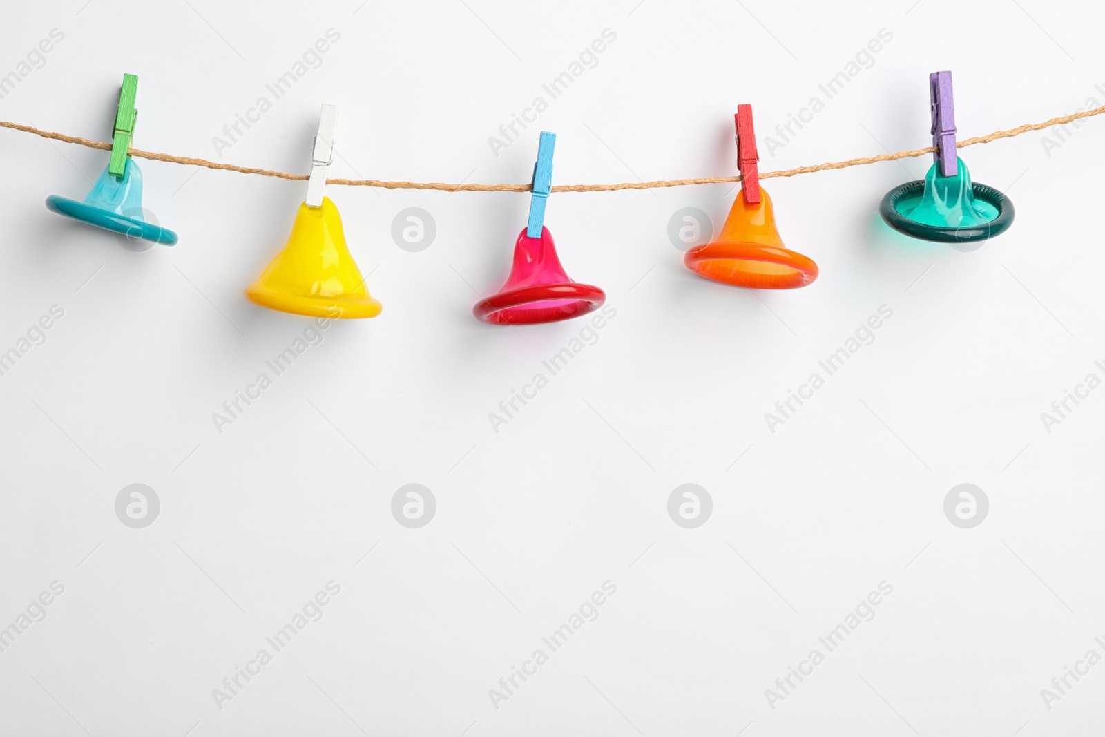 Photo of Colorful condoms hanging on clothesline against white background. Safe sex concept