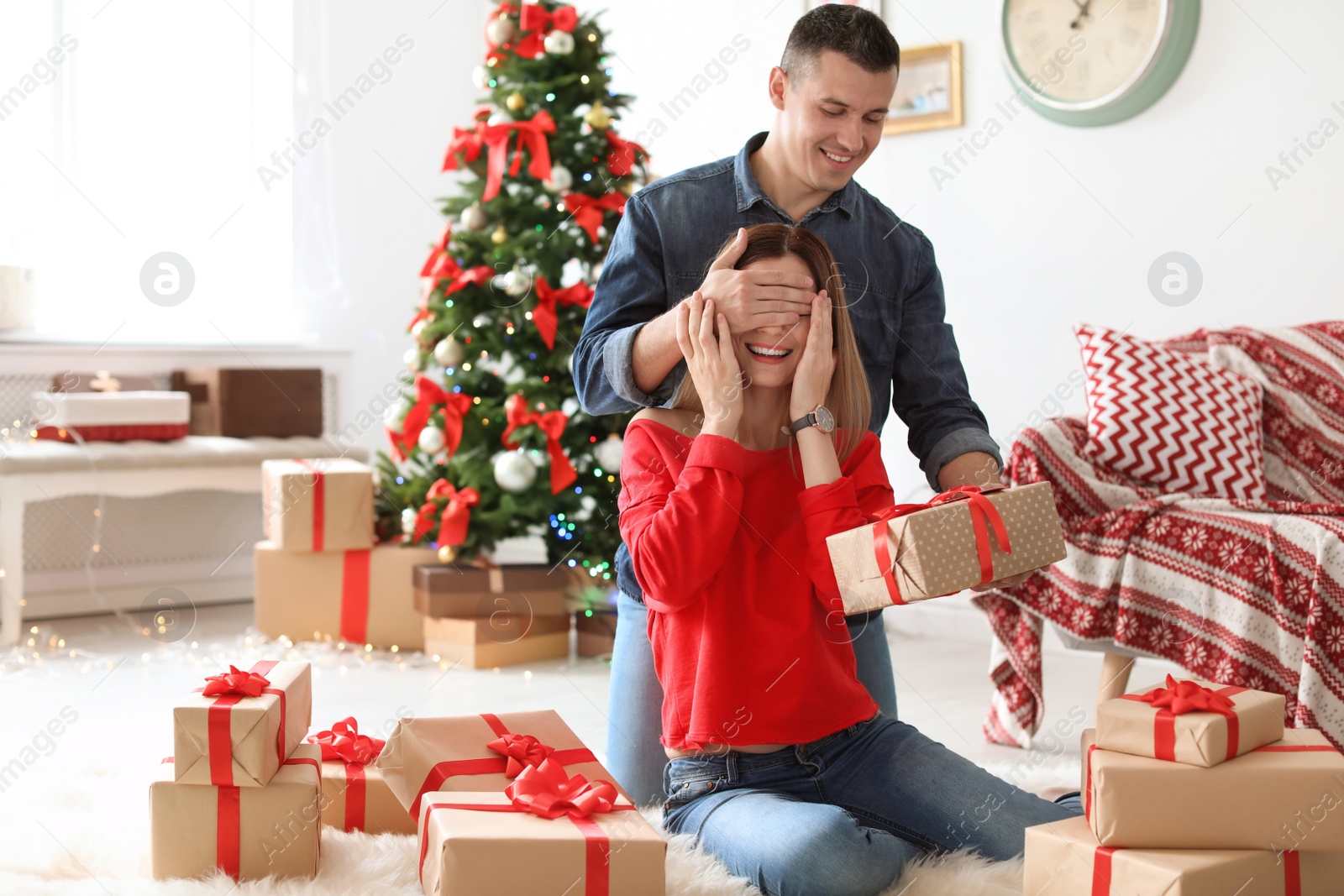 Photo of Young man surprising his girlfriend with Christmas gift at home