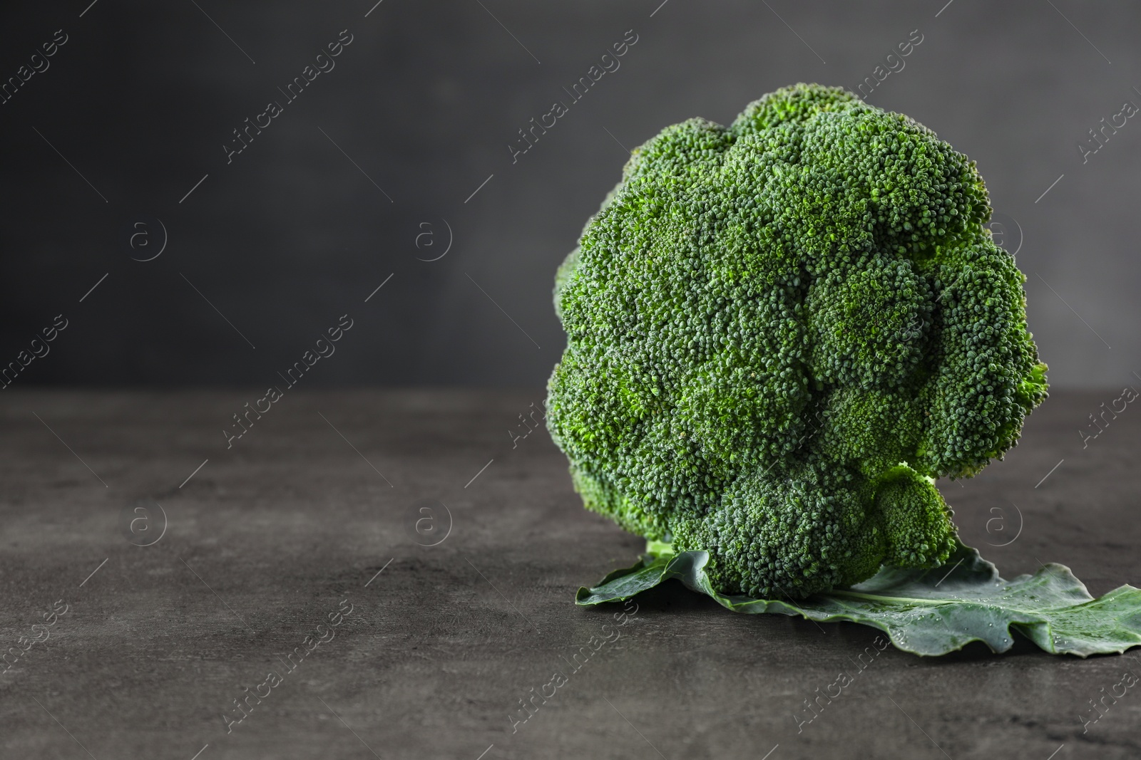 Photo of Fresh raw broccoli on grey table, closeup. Space for text