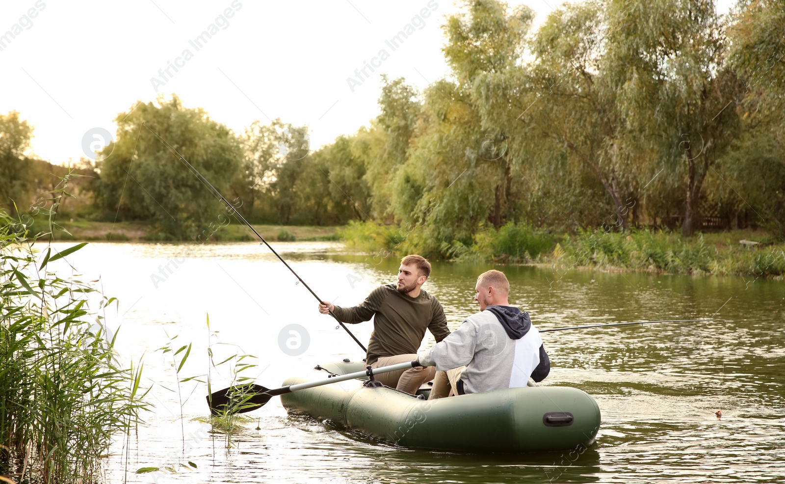 Photo of Friends fishing from boat on sunny day. Recreational activity