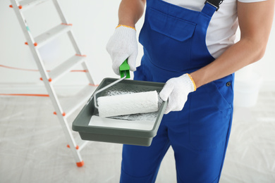 Photo of Man holding paint roller and tray in room, closeup