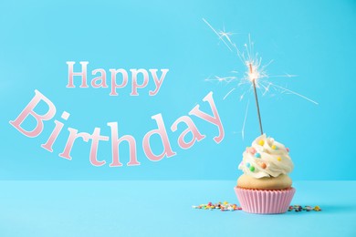 Image of Happy Birthday! Delicious cupcake with sparkler on light blue background 