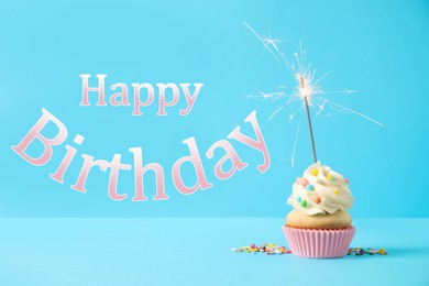 Happy Birthday! Delicious cupcake with sparkler on light blue background 