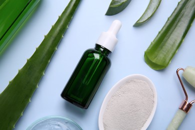 Photo of Flat lay composition with cosmetic products and cut aloe leaves on light blue background