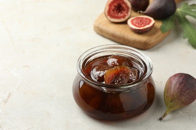 Photo of Jar of tasty sweet jam and fresh figs on white table, space for text