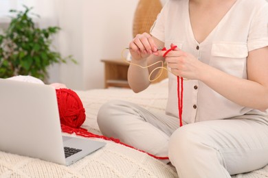 Closeup view of woman learning to knit with online course at home, space for text. Handicraft hobby