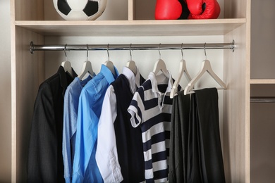 Wardrobe with stylish boy's clothes hanging on rack