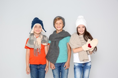 Photo of Cute little children in warm clothes posing on light background. Christmas celebration