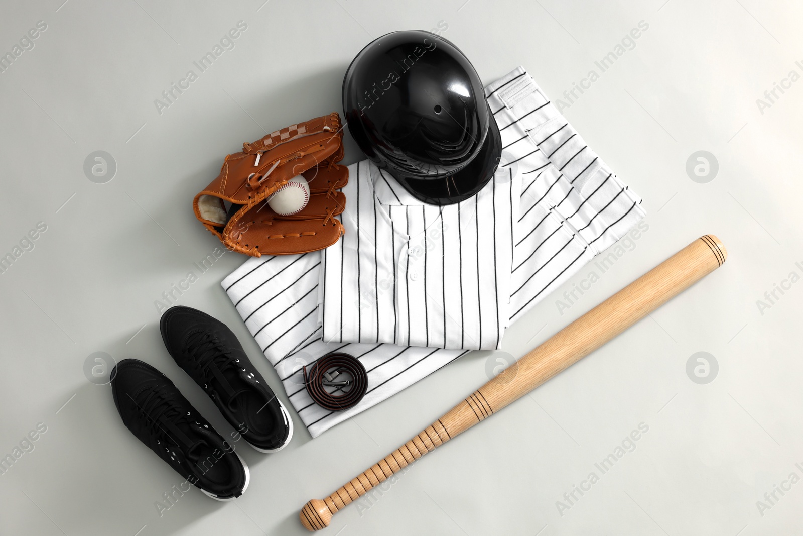 Photo of Baseball uniform and other sports equipment on white background, flat lay