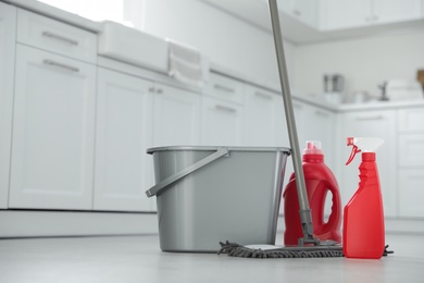 Mop, detergents and plastic bucket in kitchen. Cleaning supplies