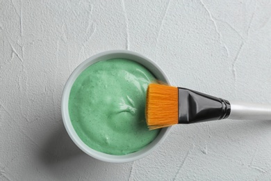 Photo of Spirulina facial mask and brush on white table, flat lay