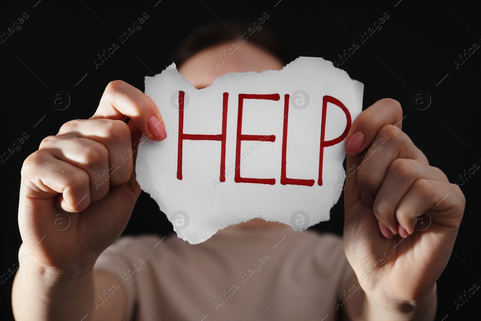 Photo of Woman holding piece of paper with word Help on black background, closeup. Domestic violence concept