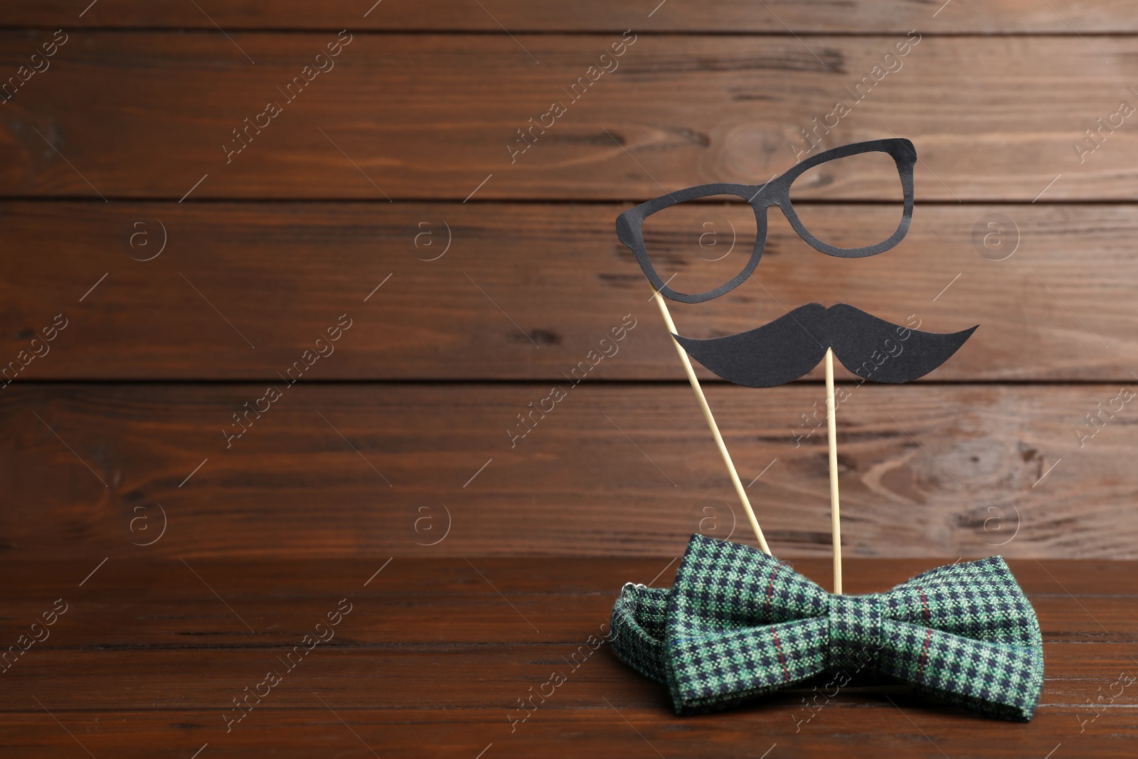 Photo of Paper moustache, glasses and bow tie on wooden background with space for text. Father's day celebration