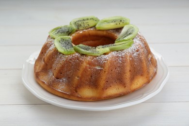 Photo of Homemade yogurt cake with kiwi and powdered sugar on white wooden table