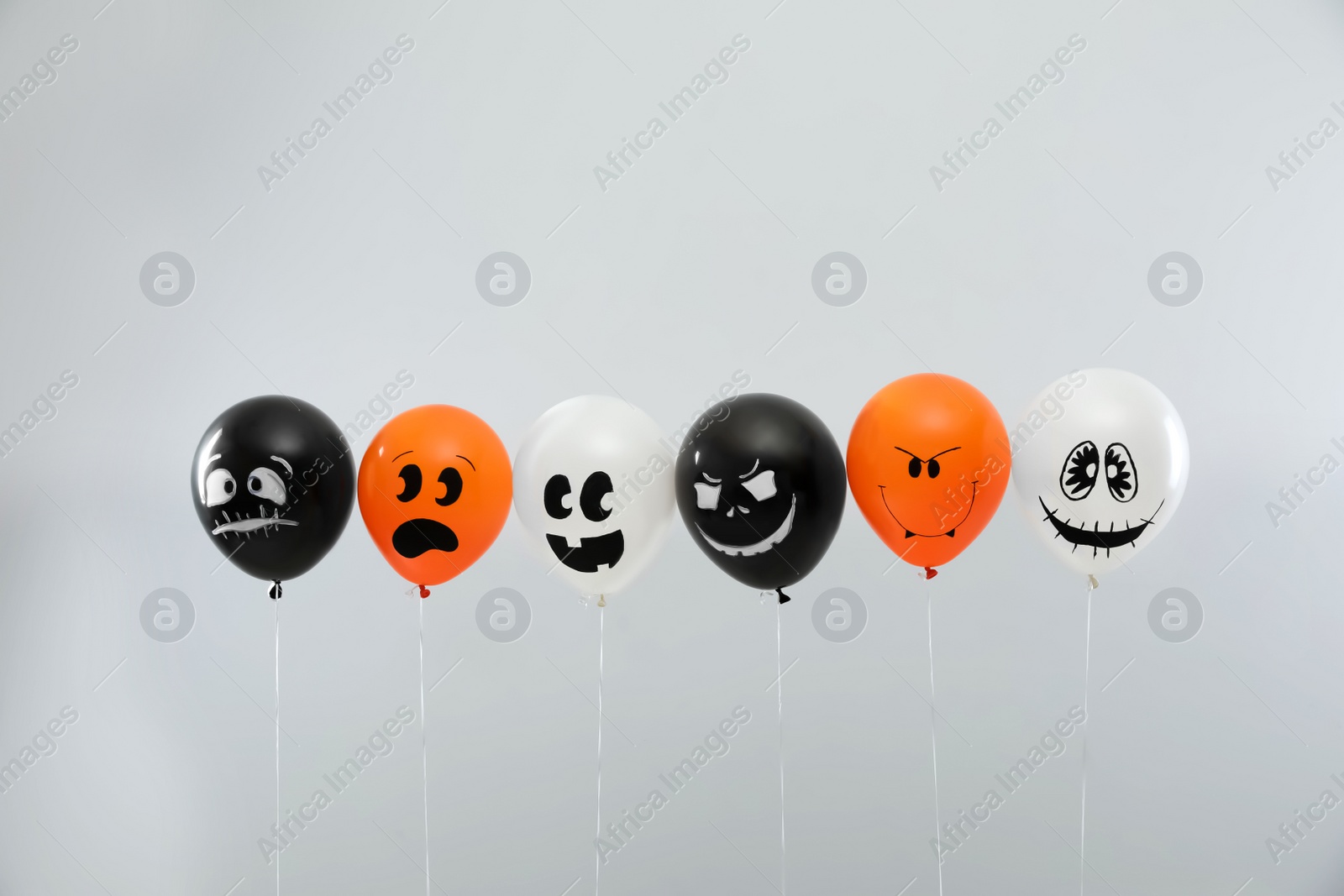 Photo of Spooky balloons for Halloween party on light grey background