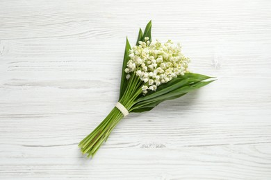 Beautiful lily of the valley bouquet on white wooden table, top view